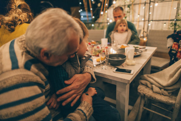 Photo of a multi-generation family having Thanksgiving dinner outdoors on their balcony