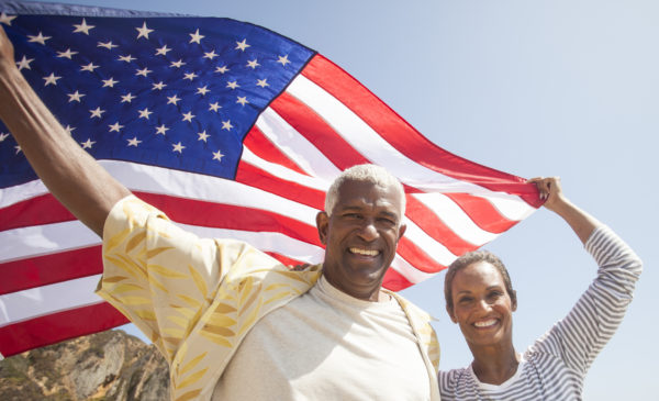 senior African American couple carrying American flag in the wind